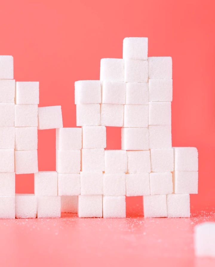 cubes de sucre empilés devant un fond rose pastel