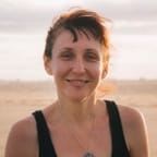 portrait d'une femme souriante sur la plage, avec les cheveux courts chatains foncé
